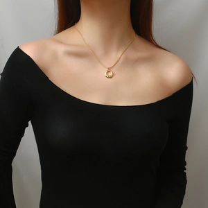 Detail of gold snake chain necklace with irregular wrinkled round pendant on model neckline