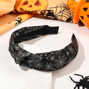 Detail of black knotted headband featuring white spider web patterns for Halloween style