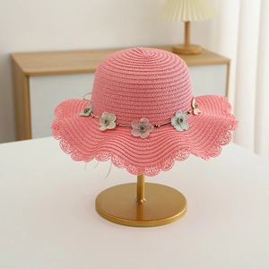 Détail du chapeau de paille rose avec bord ondulé et fleurs délicates sur un support