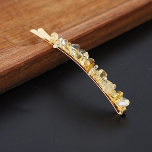 Close-up of golden hair clip featuring natural yellow crystal stone chips on wood