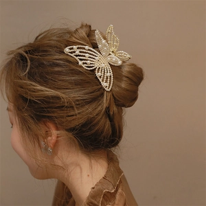 Detail of elegant butterfly hair claw clip and matching earrings with white faux pearls