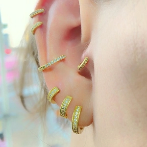 Elegant gold hoop earrings set with sparkling zircon crystals worn on earlobes and cartilage