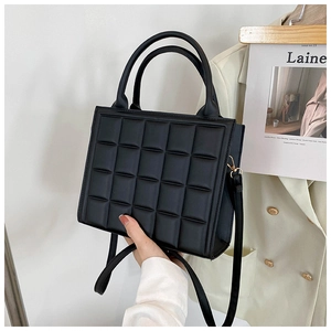 Detail of black quilted leather handbag with gold hardware and removable shoulder strap
