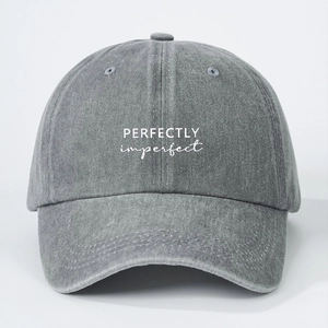 Close-up of white Perfectly Imperfect embroidery on a grey washed cotton baseball cap
