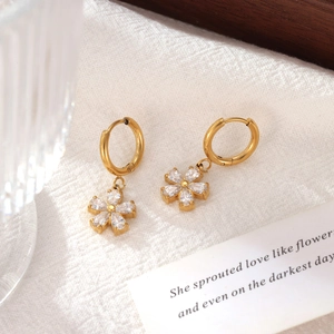 Elegant gold flower hoop earrings with sparkling zircon petals on soft fabric