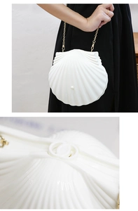 Detail of white shell evening bag with golden chain strap and pearl buckle clasp