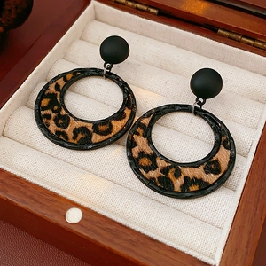 Detail view of retro leopard print hoop earrings on beige velvet jewelry tray