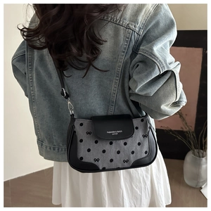 Gray polka dot crossbody bag with bow details shown on a model in a casual street setting