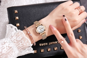 Close-up of rose gold quartz watch and crystal bracelet set on black leather bag