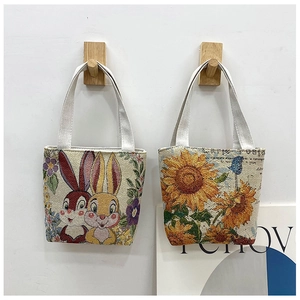 Detail of canvas tote bags featuring embroidered rabbit and sunflower patterns