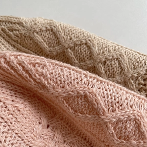 Close-up of pink and beige cotton-linen knit bucket hat showing cable stitch details