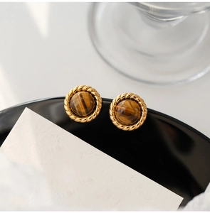 Macro shot of gold twist border earrings with polished tiger eye stone inlay
