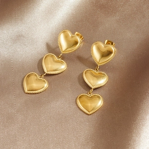 Elegant gold-plated triple heart drop earrings on a champagne silk background