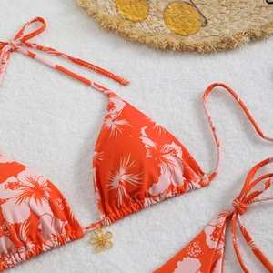 Close-up of orange tropical floral bikini top with a decorative gold flower pendant