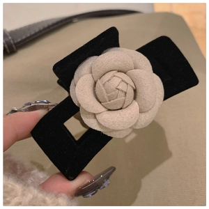 Detail view of a vintage black velvet hair claw featuring a 3D white camellia flower