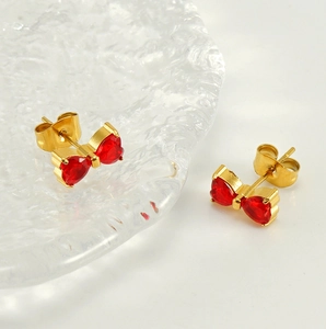 Detail of gold-plated bow earrings with vibrant red heart-shaped zircon stones