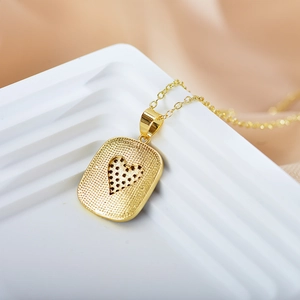 Macro shot of gold heart pendant with micro-inlaid zircons on white geometric stand