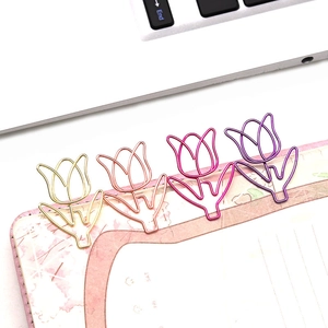 Close-up of tulip-shaped paper clips in gold and rose gold on a floral notebook edge