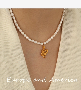 Detailed view of natural pearl necklace featuring a golden snake pendant on a model