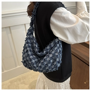 Dettaglio della borsa a spalla in denim a scacchi blu con frange e trama materica