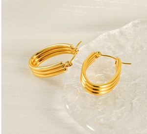 Detailed view of gold triple hoop earrings on white fabric with elegant lighting