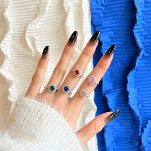 Close-up of five colorful gemstone rings with halo diamond setting on female hand
