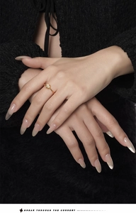 Close-up of minimalist gold ring with white agate stone on hand over black fabric
