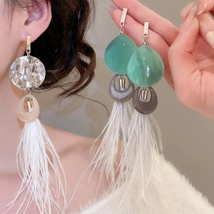 Détail de boucles d'oreilles bohèmes à pampilles en plumes avec résine et nacre