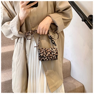 Detail of leopard print flap bag with black chain strap on stylish model in trench coat