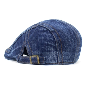 Detail view of denim beret featuring adjustable bronze buckle and washed texture