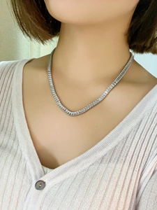 Close-up of a silver tennis necklace with rectangular cut zircons on a model's neck