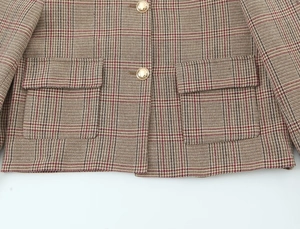 Detail of red and brown houndstooth blazer fabric with golden vintage metal buttons
