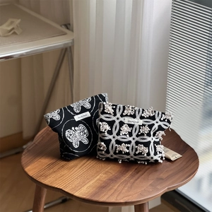 Detail view of two black canvas bags featuring white butterfly embroidery and floral patterns