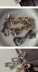 Close-up of gold and silver bow-shaped hair clips and heart patterns on a white plate