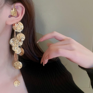 Dettaglio del ear cuff a cuore dorato con dischi in metallo martellato e nappe lunghe