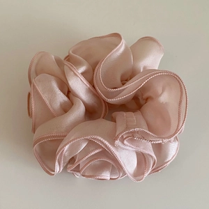 Close-up of pink sheer organza fabric texture on a pleated floral hair scrunchie
