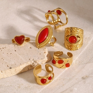 Dettaglio di sei anelli dorati con pietre di agata rossa in stile boho vintage