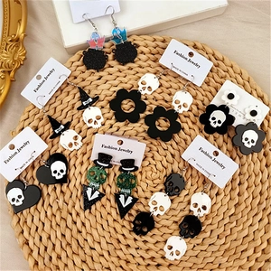Flat lay of Halloween earrings featuring skulls, ghosts and witch hats on a woven mat