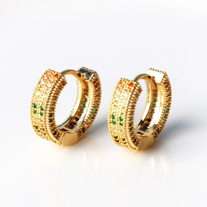 Close-up of gold huggie hoop earrings with colorful pavé stones and crystal reflection