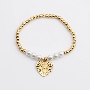 Détail d'un bracelet en perles dorées avec perles blanches et pendentif en forme de cœur