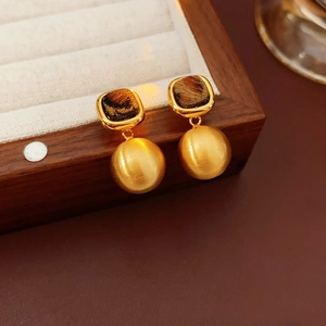 Macro shot of French vintage earrings with tortoiseshell pattern and brushed gold spheres