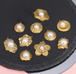 Détail de pendentifs vintage en or, fleurs et cœurs avec perles sur surface en pierre