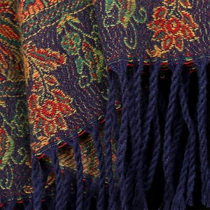 Close-up of thick core-spun yarn scarf with floral pattern and dark blue woven tassels