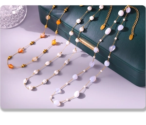 Detailopname van gouden kettingen met natuursteen en parels op een groene sieradendoos