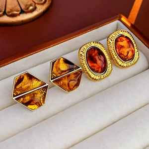 Close-up of vintage geometric resin earrings with gold-tone borders and amber textures