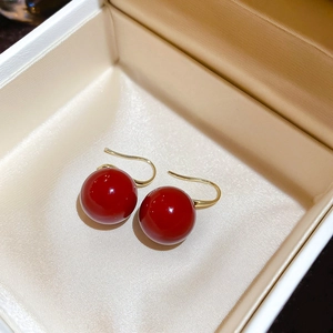 Vue détaillée de boucles d'oreilles perles rouges avec crochets dorés sur soie