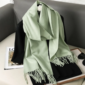 Detail of light green cashmere-like scarf showing soft texture and long fringe edges