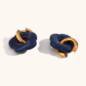 Detailed macro of gold-plated hoop earrings featuring blue marble flower resin pendants