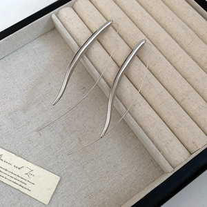 Detail view of silver teardrop dangle earrings displayed on a minimalist jewelry box