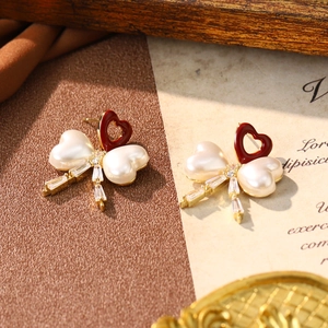 Detail of red heart earrings with white pearl bows and rhinestones on a vintage background
